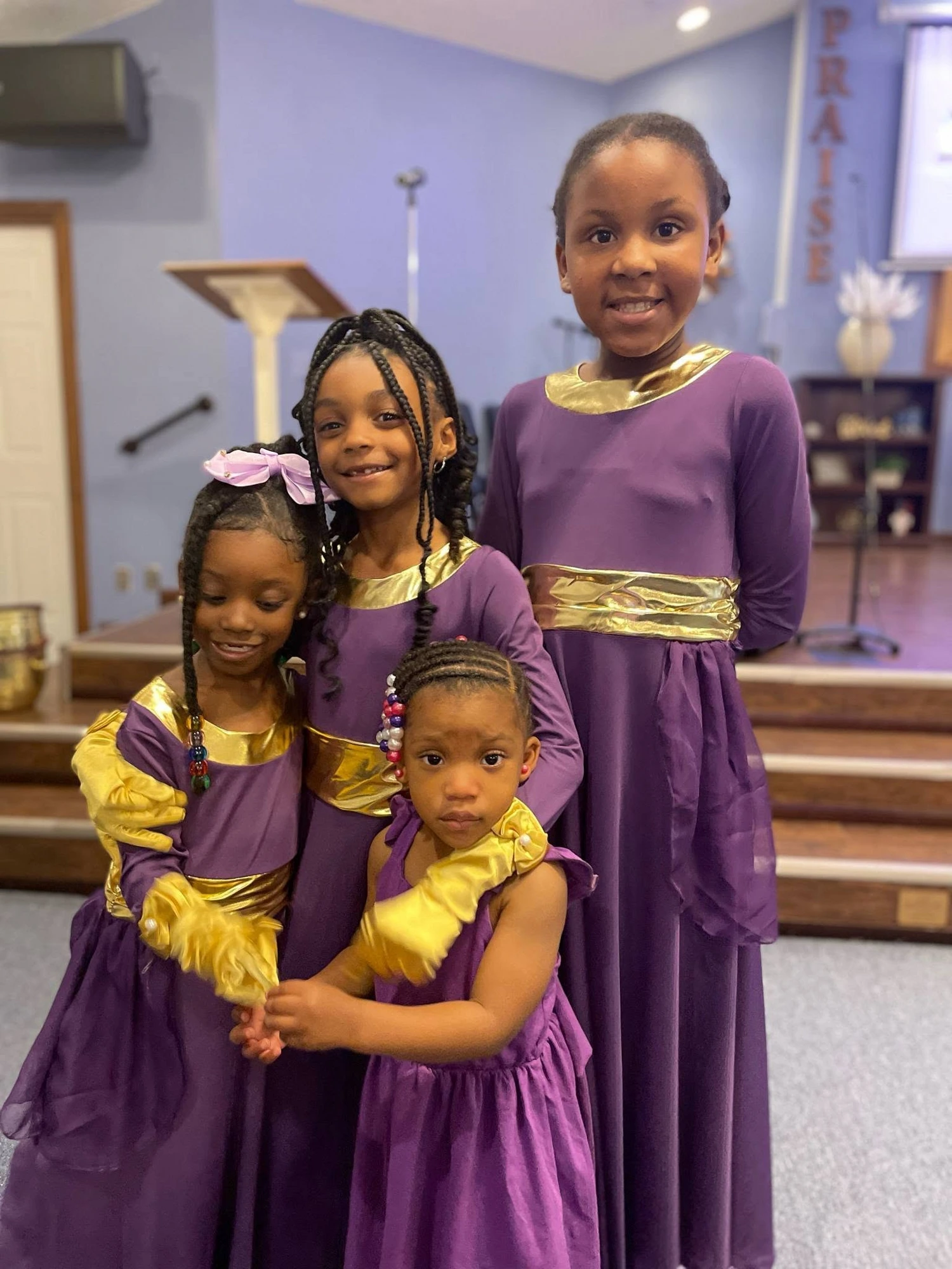 Four young praise dancers in purple and gold