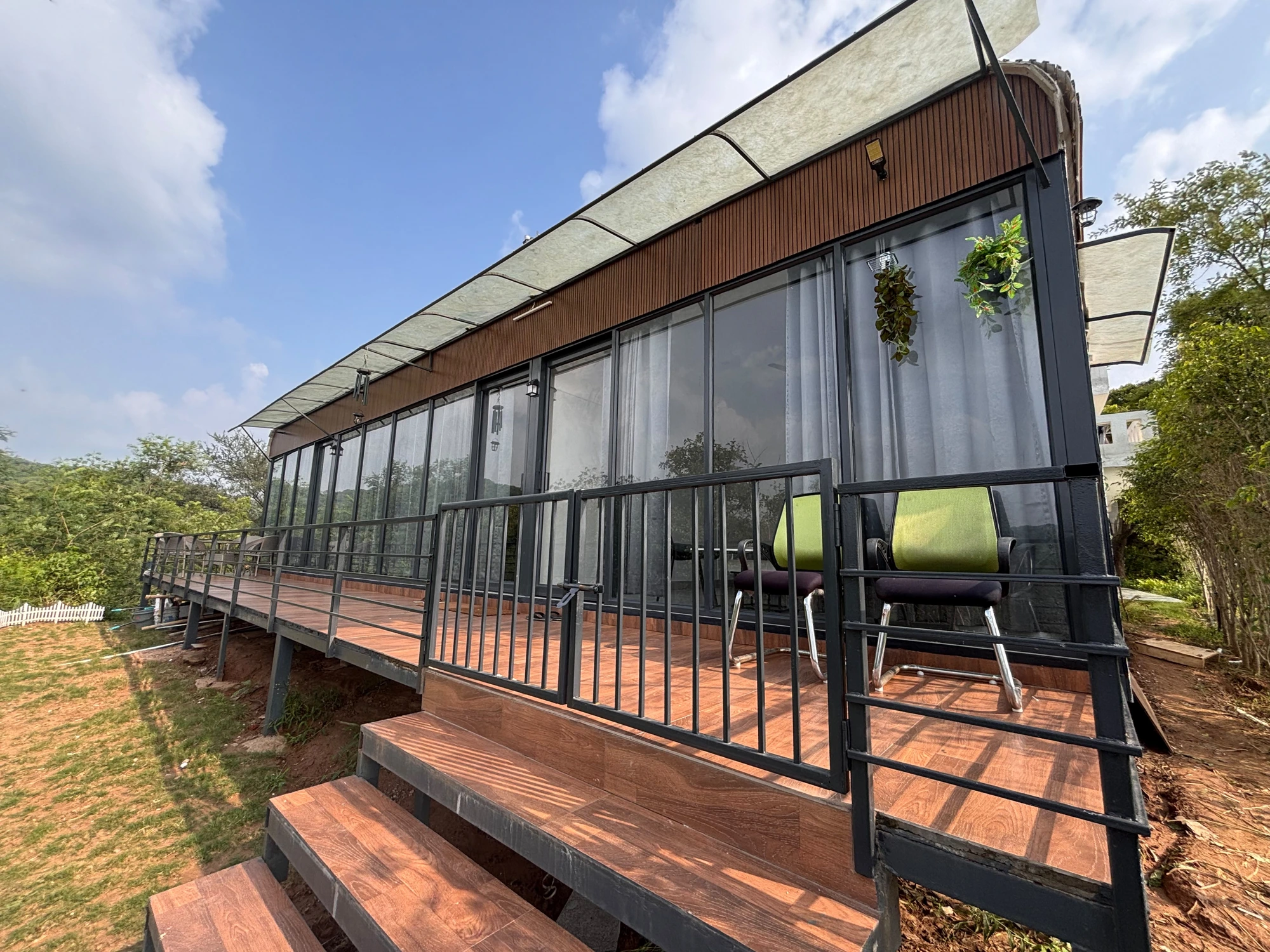 Sample Wild Grass prefab cottage exterior with glass walls, wood deck and black railings