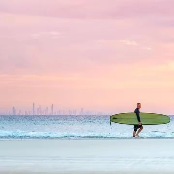 A surfer on Kirra Beach with the Surfers Paradise skyline behind