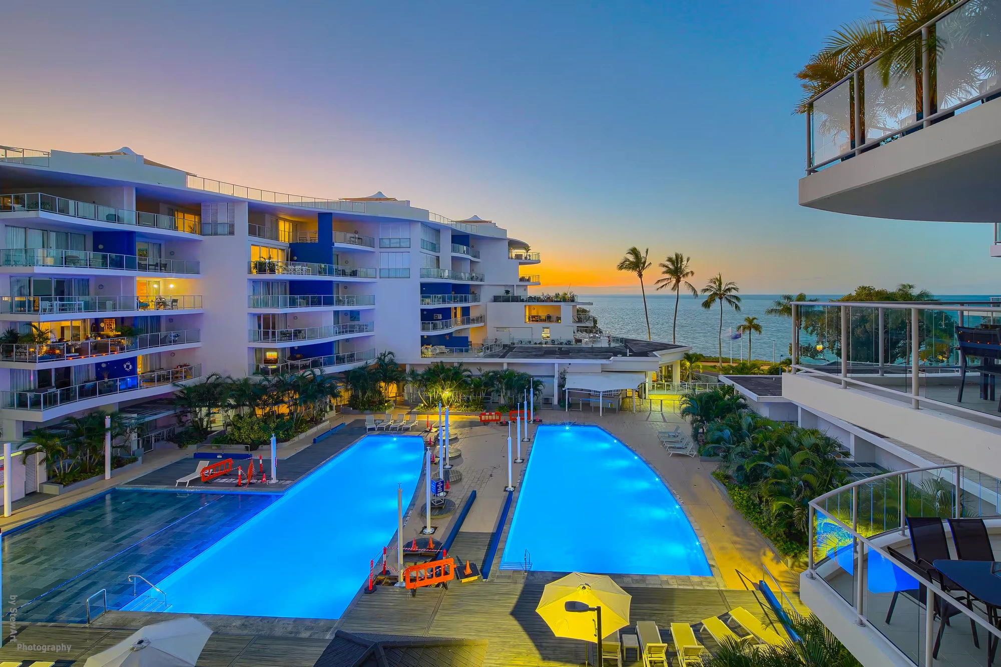 Oaks Urangan at dusk — lit pools and the ocean beyond, Hervey Bay